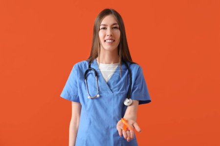 Beautiful young happy female doctor with ribbon and stethoscope on orange background. Multiple Sclerosis Awareness Month