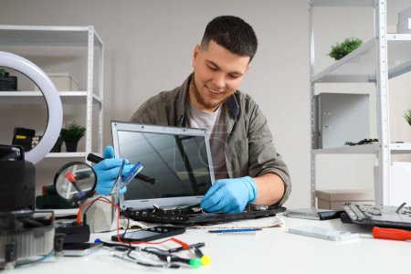 Männlicher Techniker repariert Laptop am Tisch im Service-Center