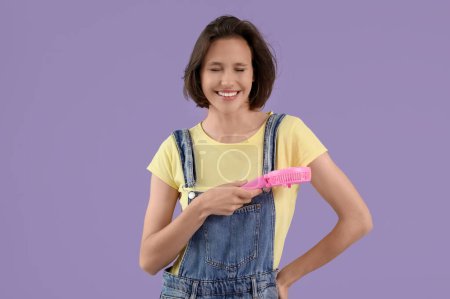 Mujer joven con ventilador eléctrico portátil rosa sobre fondo lila