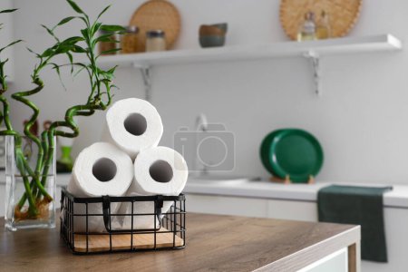 Panier avec rouleaux de serviettes en papier et tiges de bambou sur la table dans la cuisine, gros plan