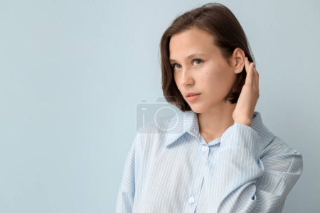 Schöne junge Frau mit Akne-Problem auf blauem Hintergrund