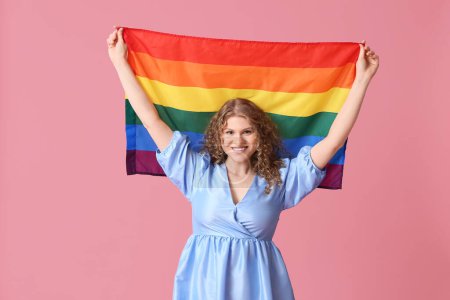 Beautiful young woman with LGBT flag on pink background