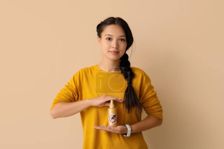 Beautiful young Asian woman with mosquito repellent spray on beige background