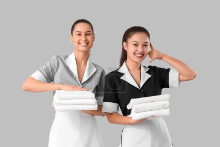 Camareras jóvenes con toallas limpias sobre fondo claro