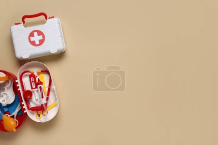 Téléchargez les photos : Trousses de premiers soins jouet sur fond beige. Vue du dessus - en image libre de droit