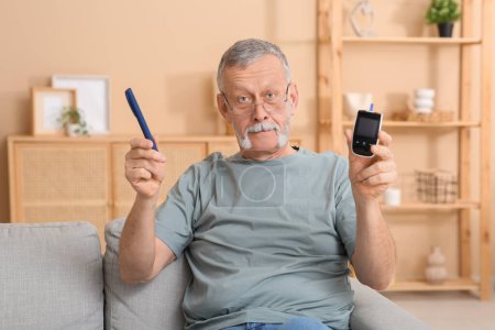 Ein älterer Mann mit Glukometer und Lanzettstift sitzt zu Hause auf dem Sofa. Diabetes-Konzept