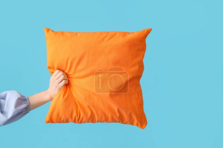 Femme avec oreiller orange vif sur fond bleu