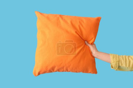 Mujer con almohada naranja brillante sobre fondo azul