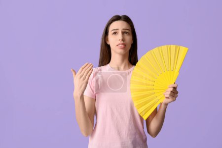 Junge hübsche Frau mit gelbem Handfächer auf fliederfarbenem Hintergrund
