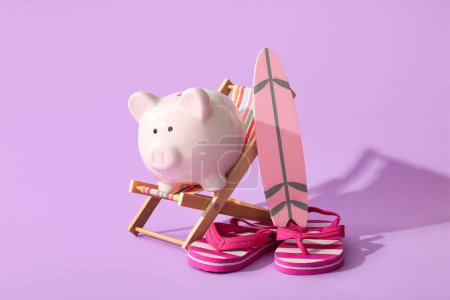 Piggy bank, decorative surfboard, deckchair and flip-flops on lilac background, closeup