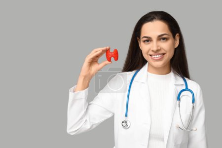 Retrato de doctora con modelo tiroideo sobre fondo gris