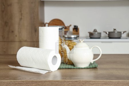 Rollos de toallas de papel con tetera y comida en la mesa en la cocina