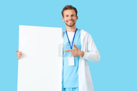 Stagiaire médical masculin pointant vers l'affiche vierge sur fond bleu