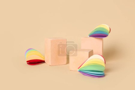 Decorative podiums with paper hearts in colors of LGBT flag on beige background. Valentine's Day celebration