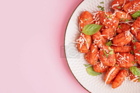Teller mit leckeren Gnocchi mit Käse auf rosa Hintergrund