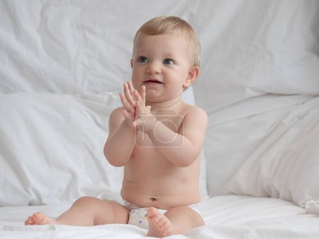 Baby clapping and playing on a bed