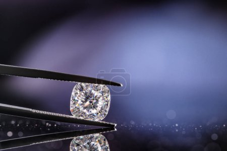 Photo for Diamond in jewelry tweezers on blue bokeh background - Royalty Free Image