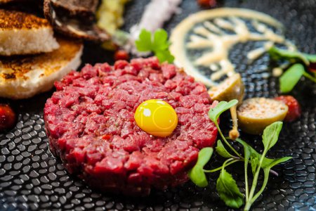 Photo for Beef tartare from Black Angus. Onion, quail egg, tomato sauce, mustard mayonnaise. Delicious healthy Italian traditional food closeup served for lunch in modern gourmet cuisine restaurant. - Royalty Free Image