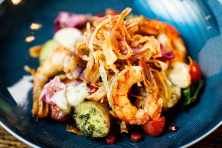 Photo for Warm salad with Argentinian king prawns. Almond potato, mini romaine lettuce, carrot, cherry tomato, pesto, black root chips, caramelized walnut, beet balsamic. Food served in modern restaurant. - Royalty Free Image