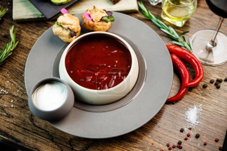 Photo for Beetroot soup Borscht with meat and sourcream in a bowl. Delicious healthy Ukrainian traditional food closeup served for lunch on a table in modern gourmet cuisine restaurant. - Royalty Free Image