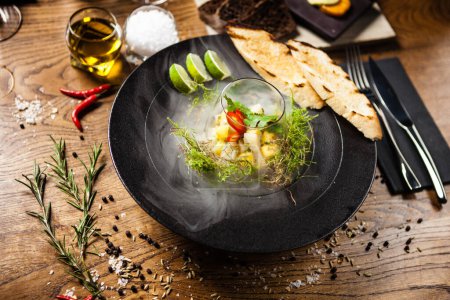Photo for Scallop ceviche with mango, chilli and cilantro served with liquid ice smoke in a plate. Delicious healthy food closeup served for lunch on a table in modern gourmet cuisine restaurant. - Royalty Free Image