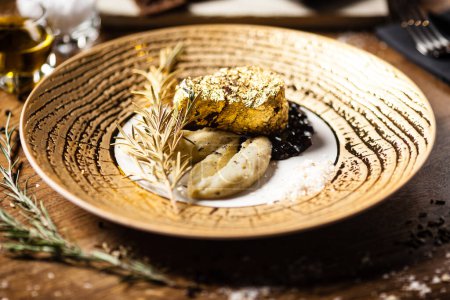 Foto de Filete de lomo negro Angus cubierto con oro de 24 quilates, puré de papas, salsa de vino tinto con bayas, rosmarine - Imagen libre de derechos