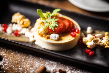 Photo for Toffee Panna Cotta with strawberries and caramelized popcorn on a plate. Delicious healthy food closeup served for lunch on a table in modern gourmet cuisine restaurant. - Royalty Free Image
