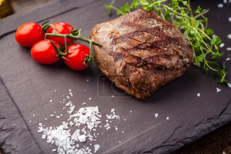 Téléchargez les photos : Steak d'agneau aux tomates cerises et sauce au vin. Délicieuse cuisine traditionnelle saine servie en gros plan pour le déjeuner dans un restaurant gastronomique moderne. - en image libre de droit