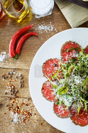 Photo for Beef carpaccio. Borettane onion, sun-dried tomato, truffle dressing, arugula salad, parmesan cheese. Italian traditional antipasti snacks served for lunch with wine in modern gourmet restaurant. - Royalty Free Image