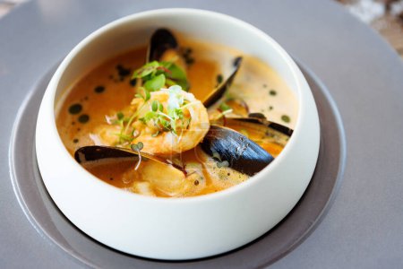 Photo for Shrimp Bisque with Seafood. King prawn, blue mussels, cod, whipped cream. Delicious traditional food closeup served for lunch in modern gourmet cuisine restaurant. - Royalty Free Image