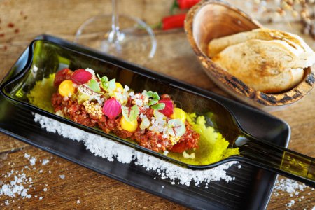 Photo for Beef tartare from Black Angus. Egg yolk, pickled cucumber, shallot, pearl onion, coriander and mustard seeds. Delicious healthy Italian food served for lunch in modern gourmet cuisine restaurant. - Royalty Free Image