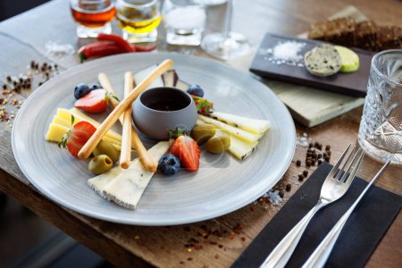 Photo for Cheese platter for two: Goat cheese cream, gorgonzola, camembert, grissini and fig jam. Delicious healthy Italian traditional food closeup served for lunch in modern gourmet cuisine restaurant. - Royalty Free Image