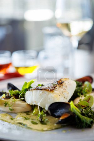 Photo for Cod fillet with cauliflower cream, asparagus, clam-wine sauce and mussles. Delicious seafood fish closeup served on a table for lunch in modern cuisine gourmet restaurant. - Royalty Free Image