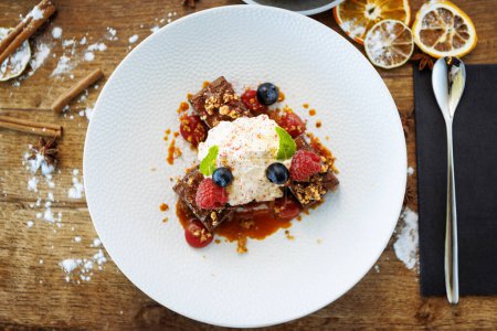 Photo for Brownie cake with salted caramel. Anglaise foam, raspberry sauce, praline nut and fresh berry. Delicious sweet dessert food closeup served for lunch in modern gourmet cuisine restaurant. - Royalty Free Image