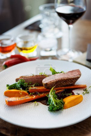 Photo for Duck fillet with sweet potato cream, roasted carrots, kale, beet-port sauce on white plate. Grilled and roasted poultry closeup served on a table for lunch in modern cuisine gourmet restaurant - Royalty Free Image