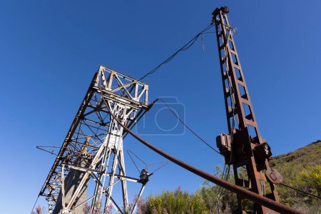 Abandoned industrial coal mining steel structure tower from cableway with cable in Tormaleo Asturias province of Spain on a bright sunny day.