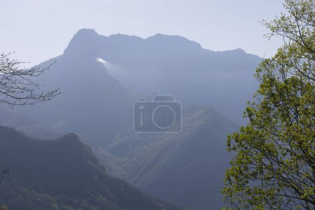 Paisaje de montaña con pico y nube en un soleado día de primavera con vegetación verde y cielo azul en el Parque Nacional Picos de Europa en el norte de España.