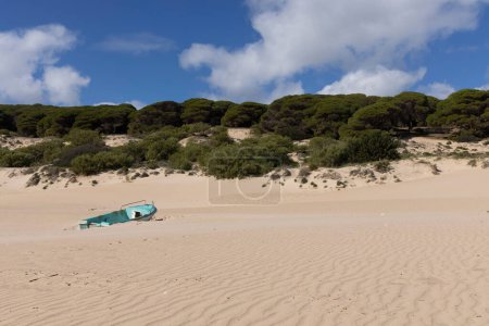 Barco de pesca en la playa de arena junto al océano en Punta Paloma en España en un día soleado brillante con cielo azul.