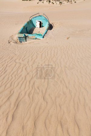 Barco viejo abandonado en la orilla del mar varado y lleno de arena en Punta Paloma en un día soleado brillante con cielo azul.
