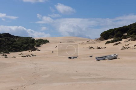 Bateau de pêche abandonné sur la plage à côté de l'océan sur le sable avec une journée ensoleillée et un ciel bleu.