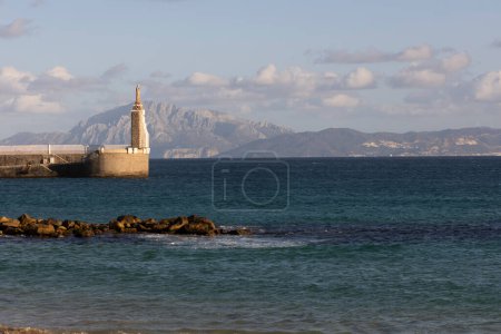 Jesus statue in harbour of Tarifa at the strait of Gibraltar with view to Morocco on a bright sunny day with cloudy sky.