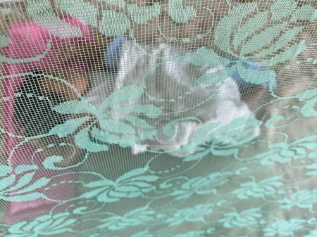 Asiática chica duerme en su cuna y se extiende un mosquitero
