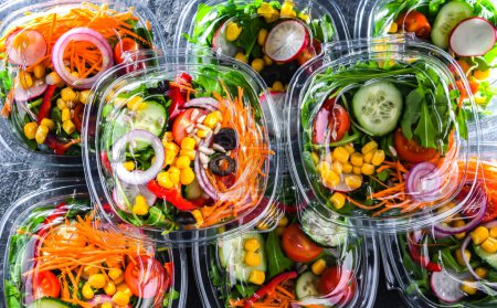 Cajas de plástico con ensaladas de verduras preenvasadas, puestas a la venta en un refrigerador comercial