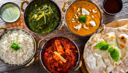 Composition with indian dishes: madras paneer, palak paneer and shahi paneer with basmati rice served in original indian karahi pots.