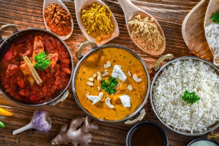 Foto de Composición con platos indios: madras paneer, palak paneer y shahi paneer con arroz basmati servido en macetas karahi indias originales. - Imagen libre de derechos