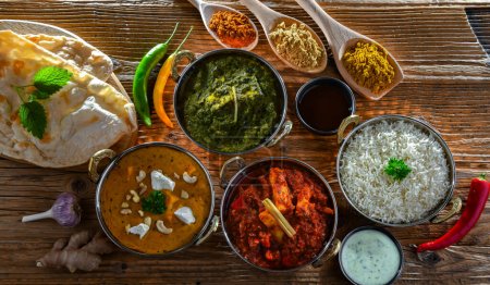 Photo for Composition with indian dishes: madras paneer, palak paneer and shahi paneer with basmati rice served in original indian karahi pots. - Royalty Free Image