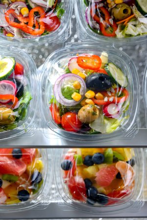 Foto de Cajas de plástico con ensaladas de verduras preenvasadas, puestas a la venta en un refrigerador comercial - Imagen libre de derechos