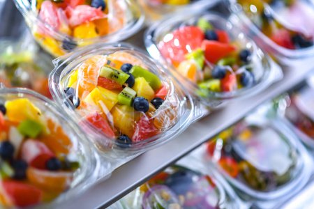 Photo for Plastic boxes with pre-packaged fruit salads, put up for sale in a commercial refrigerator - Royalty Free Image