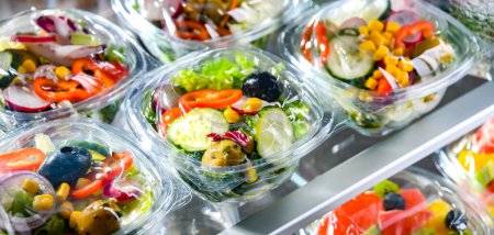 Téléchargez les photos : Plastic boxes with pre-packaged fruit and vegetable salads, put up for sale in a commercial refrigerator - en image libre de droit