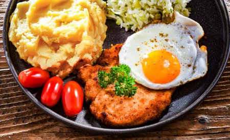 Photo for Breaded chicken cutlet served with fried chicken egg, potatoes and cabbage - Royalty Free Image